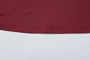 Dettaglio macro dell'orlo del vestito rosso vino con cuciture di qualità e trama del tessuto