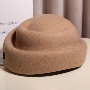 Detail of wool felt camel bowler hat with rolled brim and vintage round logo decoration