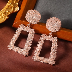 Detailed view of rose gold geometric square earrings with hammered texture on silk fabric