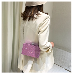 Detailed view of purple sequin box bag with silver chain strap on model shoulder