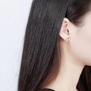 Gros plan détaillé d'une boucle d'oreille papillon dorée avec émail blanc sur un modèle