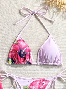 Detail of floral printed bikini top and side-tie bottoms on textured carpet