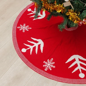 Red knitted Christmas tree skirt with white snowflake patterns on wooden floor 120cm