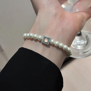 Detailed macro view of an elegant pearl bracelet with a vintage-style blue gemstone