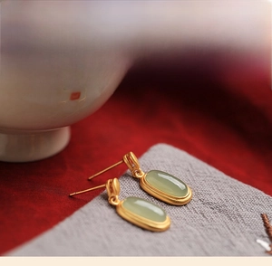 Macro shot of vintage Hetian jade earrings with matte gold floral enamel details