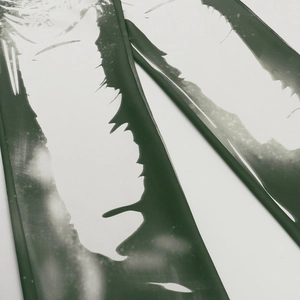Detailed macro view of dark green fabric showing abstract white print and fine stitching