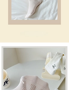 Detailed knit of beige mesh socks featuring black letter embroidery and breathable holes