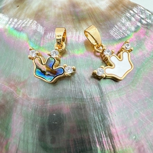 Macro shot of 18K gold crown pendants with natural white shell and abalone shell inlay