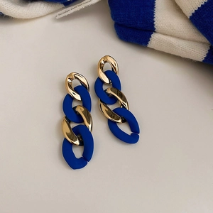 Detail of Klein blue and gold chain earrings on a white background with knitwear