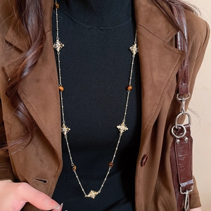 Detail of vintage gold tiger eye cross pendant necklace on a black turtleneck sweater