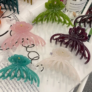 Detail showing five translucent floral hair claws in pink, green, purple, blue, and white
