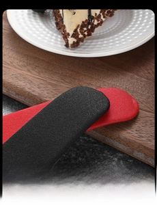 Close-up of stainless steel ice clip with ergonomic red and black matte handle on wood