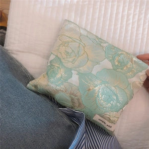 Close-up of golden rose jacquard embroidery on a mint green floral cosmetic pouch