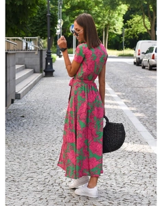 Detail view of long green floral dress with v-neck and waist tie on a street backdrop