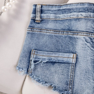 Dettaglio ravvicinato di pantaloncini di jeans blu con cuciture in vita e frange