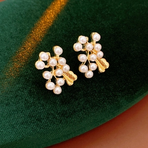 Close-up of vintage gold flower earrings with white pearl clusters on green velvet