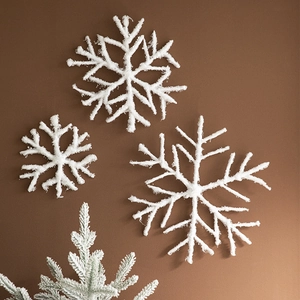 White glittery Christmas snowflake ornaments in three sizes on dark background