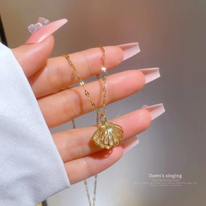 Handheld view of a gold shell pearl pendant necklace with a fine curb chain design