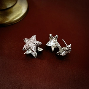 Elegant silver star stud earrings with white cubic zirconia on leather background