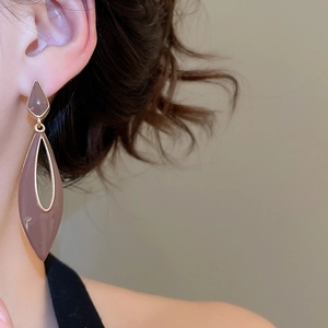 Close-up of geometric drop earrings in mauve and gold finish worn by model