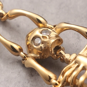Golden stainless steel skull bracelet with sparkling cubic zirconia eyes and bone textures