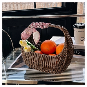 Detail of hand-woven wicker basket bag with pink floral scarf on a modern glass shelf