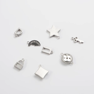 Stainless steel DIY jewelry charms including star, key, and lock pendants on white backdrop