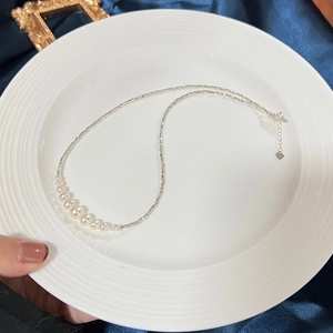 Macro view of a s925 silver necklace featuring gradient freshwater pearls on a ceramic plate