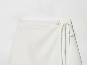 Detail of elegant white woven skirt featuring waist button and side bow tie ribbon
