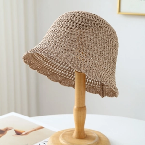 Detail of khaki crochet bucket hat with hollow knit texture on a wooden stand