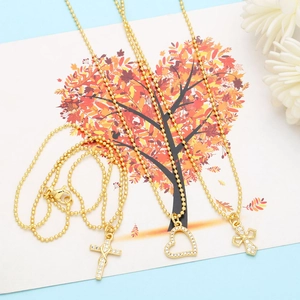 Detailed shot of gold bead necklaces with heart and cross pendants inlaid with zircon