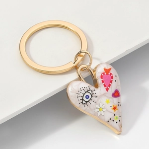 Porte-clés cœur doré avec motif œil bleu et marguerites sur texture de marbre blanc