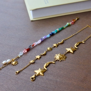 Detail of star and moon charms on gold stainless steel bracelets with boho stones