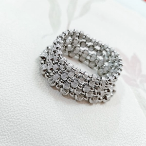 Macro shot of silver beaded stretch bracelet with intricate textured metallic weaving