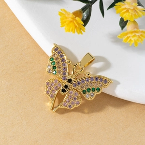 Macro shot of 3D gold butterfly pendant with colorful zircon stones on matte surface