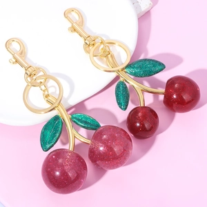 Macro detail of cherry keychains with red glitter resin fruits and gold lobster clasps