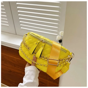 Detail view of yellow quilted waist bag with tassel zippers and golden chain strap