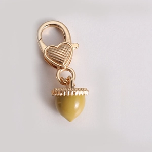 Detail view of heart-shaped gold clasp with a yellow-green acorn pendant accessory