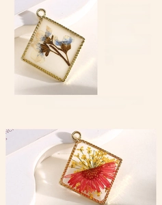 Detail of square alloy pendant with real red and blue dried flowers in resin