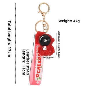 Detail view of a red astronaut keychain with pink strap showing 17cm total length dimensions
