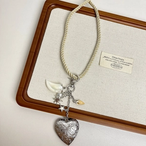 Detail of bohemian necklace with woven rope, heart relief, sea shell and celestial charms