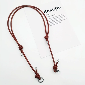 Close-up of a reddish brown braided leather shoulder strap with gold-tone metal knots