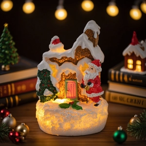 Lighted Christmas gingerbread house with Santa figurine and warm LED glow for table decor