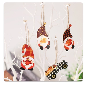 Detail of wooden gnome ornaments with pumpkins and turkey hanging on a white festive tree