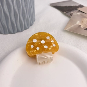 Detail der gelben Acetat-Pilz-Haarklammer mit weißen Punkten auf einem Keramikteller
