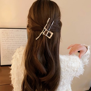 Golden geometric safety pin hair claw clip worn on a partial updo hairstyle