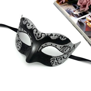Detail of a black and silver glitter masquerade mask with ribbons and floral patterns