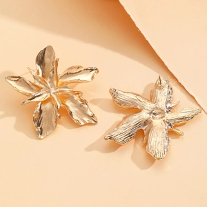 Macro detail of large gold flower studs showing textured petals and needle back