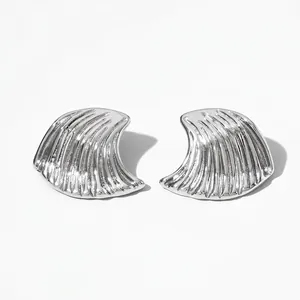 Gros plan sur des boucles d'oreilles argentées en éventail avec texture ondulée 3D