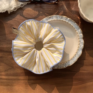 Close-up of yellow striped scrunchie with blue edging on a vintage ceramic plate